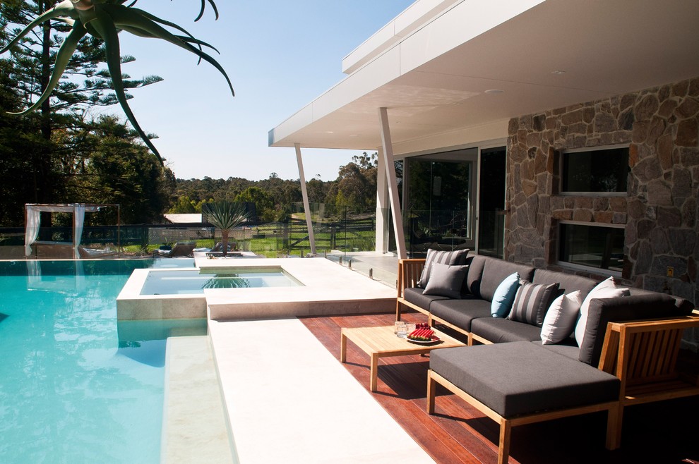 This is an example of a large modern backyard custom-shaped pool in Sydney with decking.