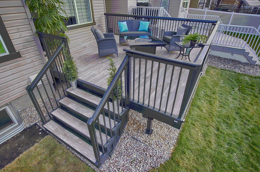 Example of a mid-sized transitional backyard deck design in Calgary with a fire pit and no cover