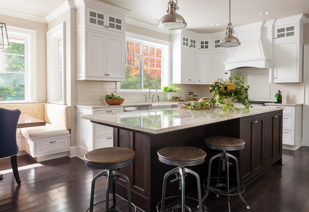 Design ideas for a large arts and crafts u-shaped open plan kitchen in Seattle with a farmhouse sink, beaded inset cabinets, white cabinets, quartzite benchtops, white splashback, ceramic splashback, stainless steel appliances, dark hardwood floors, with island and brown floor.