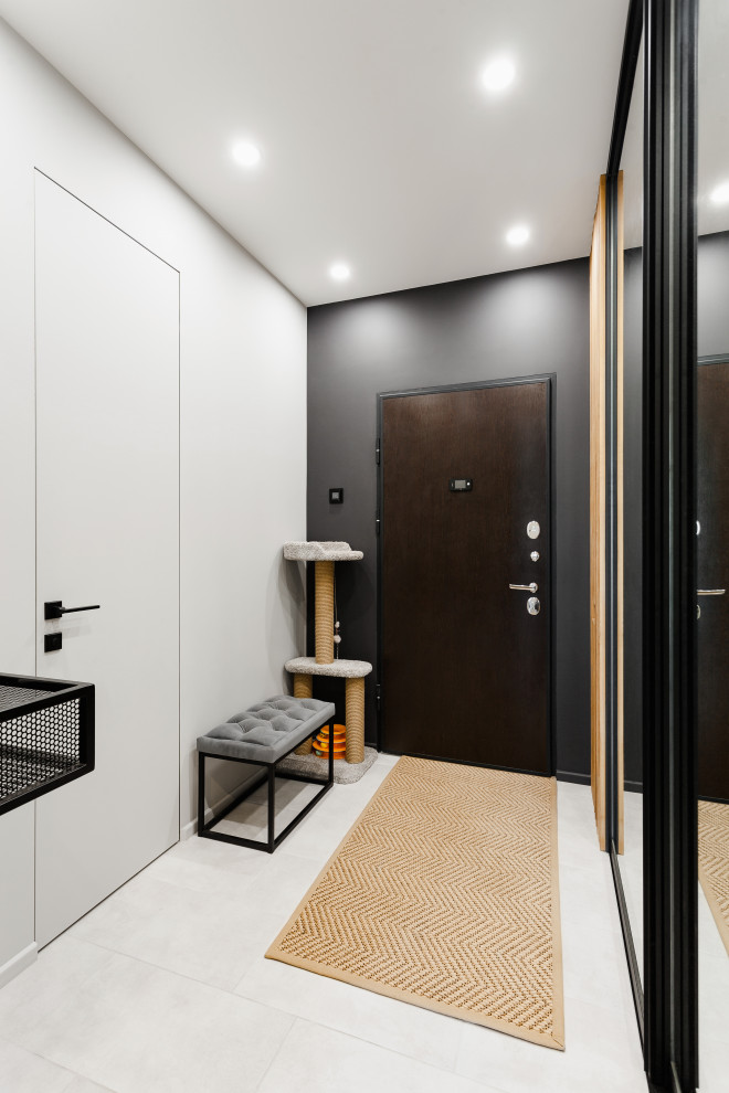 This is an example of a small contemporary front door in Moscow with black walls, porcelain floors, a single front door, a dark wood front door, grey floor and panelled walls.
