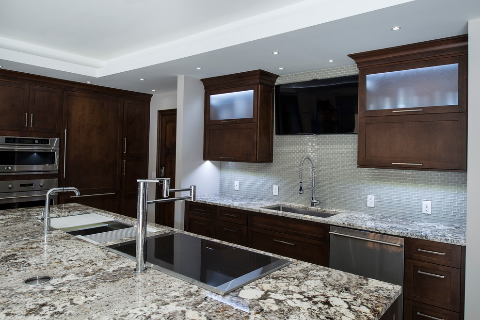Large transitional ceramic tile and beige floor eat-in kitchen photo with an undermount sink, shaker cabinets, brown cabinets, granite countertops, white backsplash, stainless steel appliances, an island and glass tile backsplash