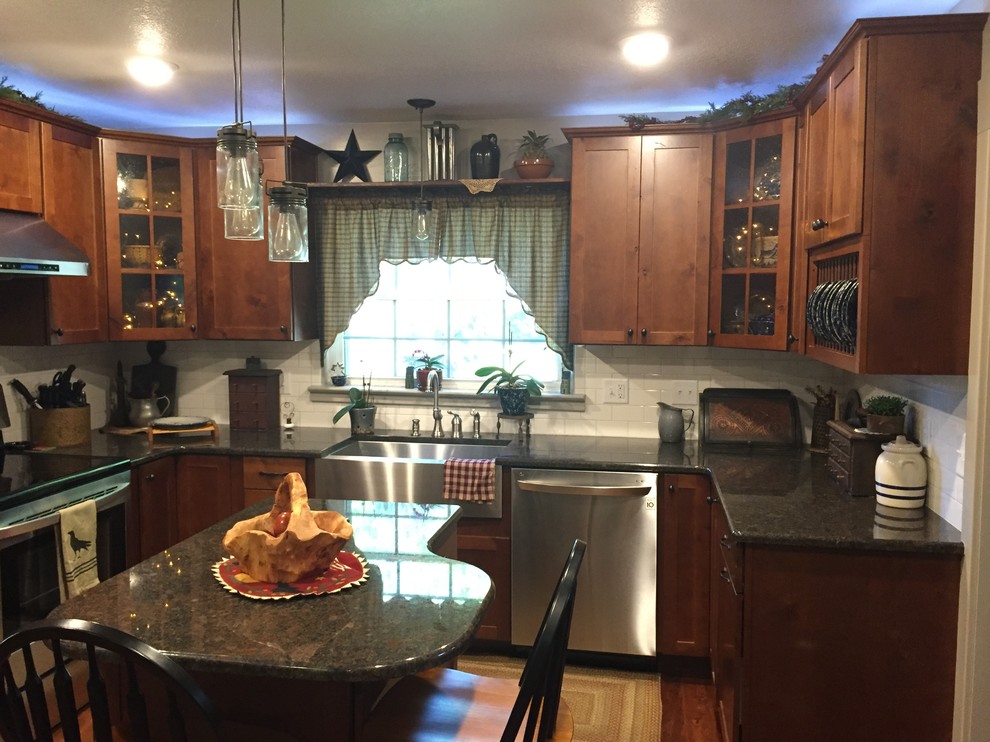 Mid-sized transitional u-shaped enclosed kitchen photo with a farmhouse sink, shaker cabinets, medium tone wood cabinets, granite countertops, white backsplash, stainless steel appliances and an island