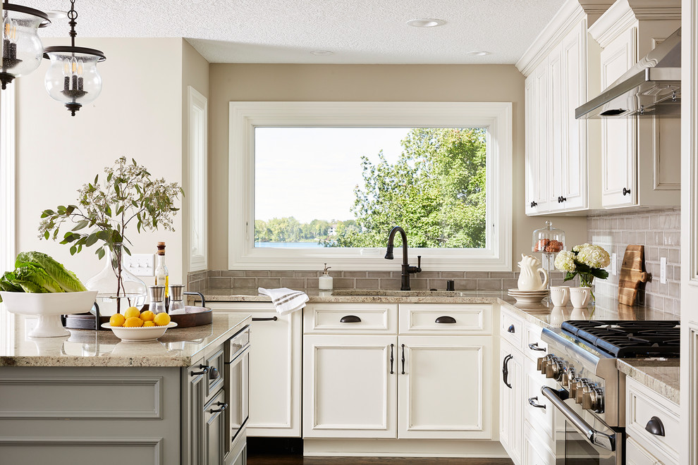 Inspiration for a large traditional l-shaped kitchen in Minneapolis with an undermount sink, recessed-panel cabinets, white cabinets, granite benchtops, grey splashback, subway tile splashback, stainless steel appliances, dark hardwood floors, with island, brown floor and beige benchtop.
