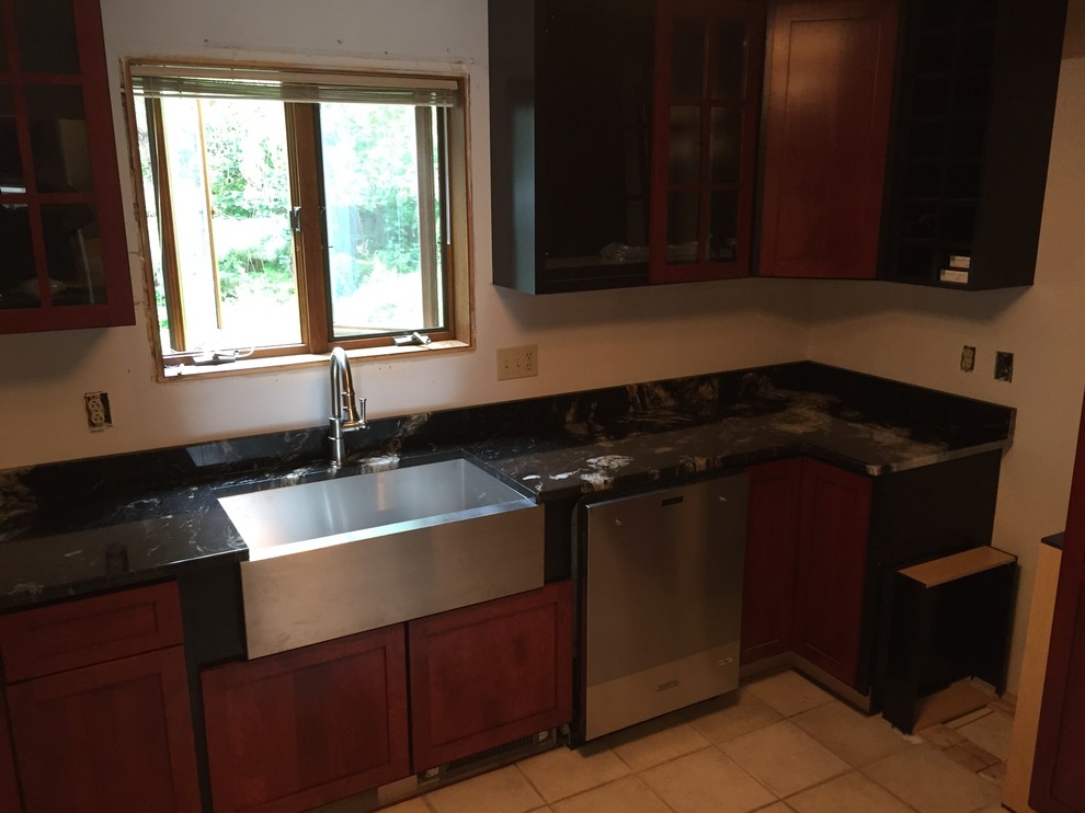 This is an example of a mid-sized modern single-wall open plan kitchen in Other with a farmhouse sink, flat-panel cabinets, dark wood cabinets, granite benchtops, stainless steel appliances, porcelain floors and with island.
