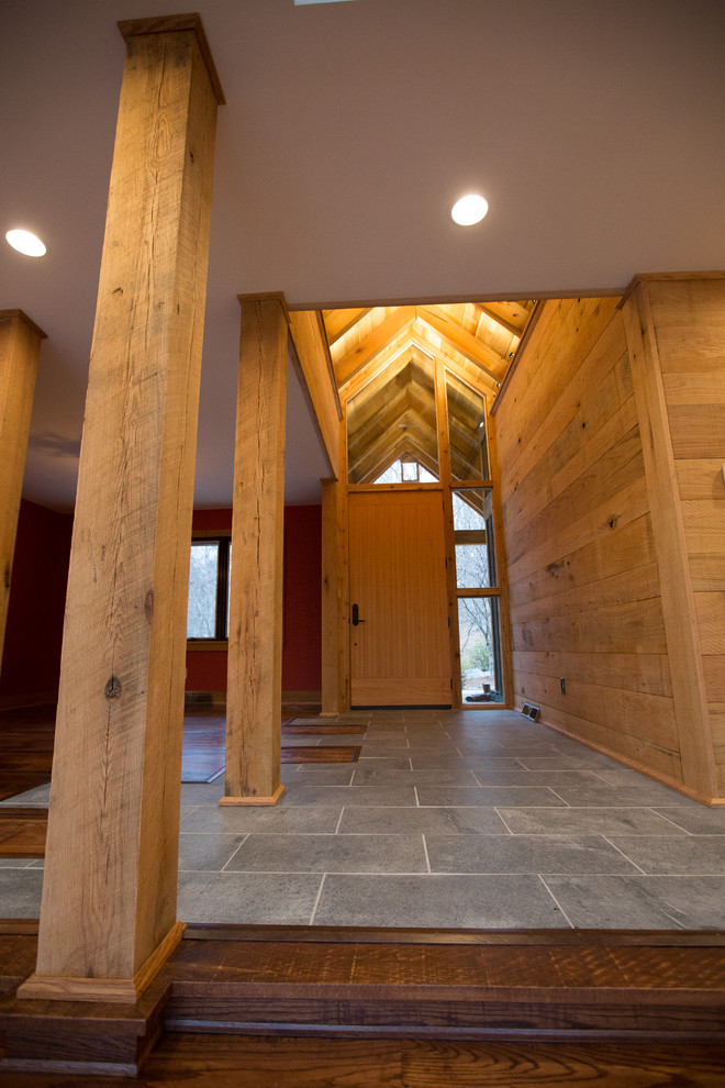 Example of a large mountain style ceramic tile foyer design with brown walls and a medium wood front door