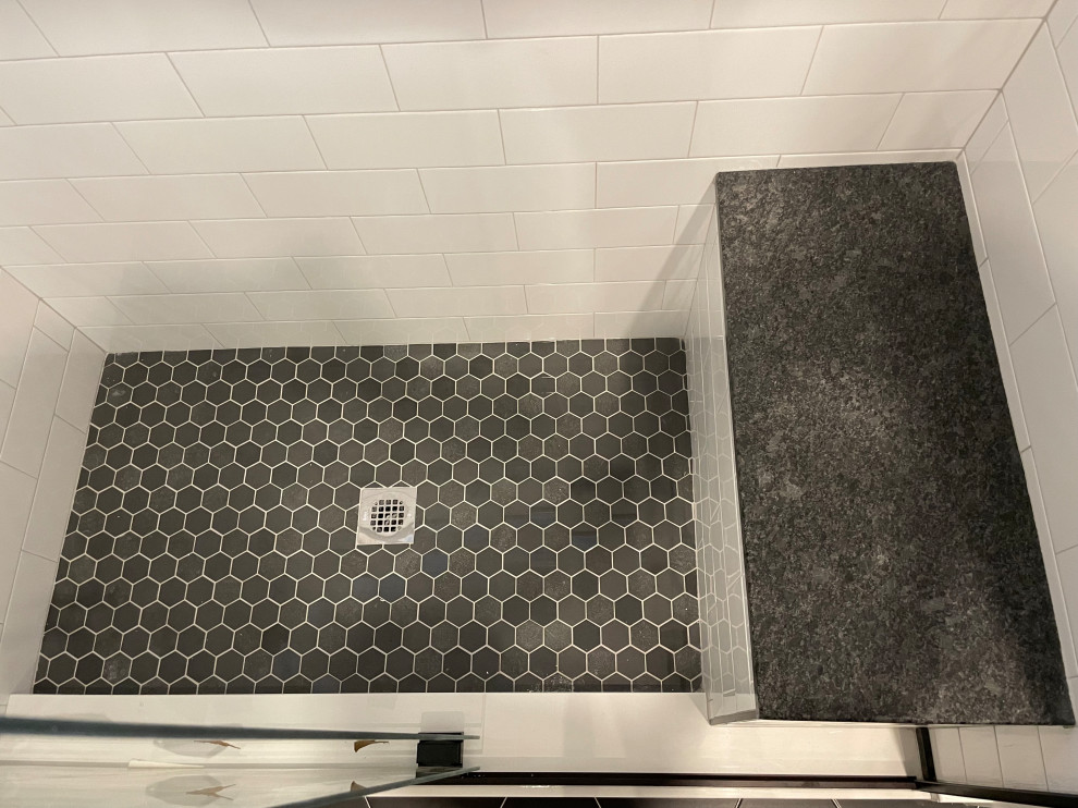 Mid-sized modern master bathroom in DC Metro with flat-panel cabinets, brown cabinets, an alcove shower, white tile, porcelain tile, grey walls, porcelain floors, an undermount sink, granite benchtops, black floor, a sliding shower screen, black benchtops, a shower seat, a double vanity and a floating vanity.