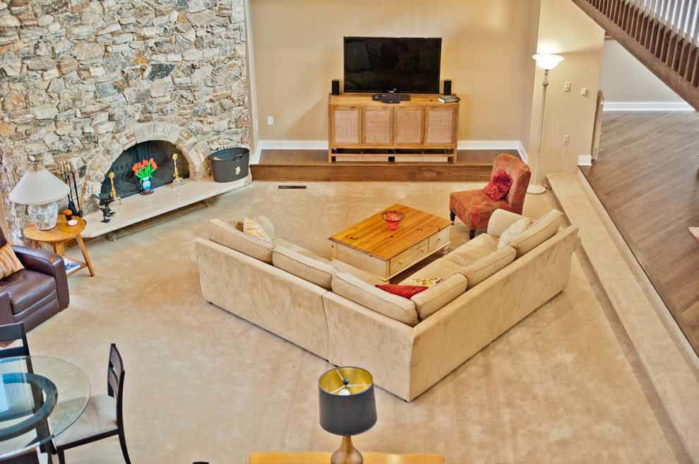Photo of an expansive traditional open concept family room in New York with beige walls, carpet, a standard fireplace, a stone fireplace surround and a freestanding tv.