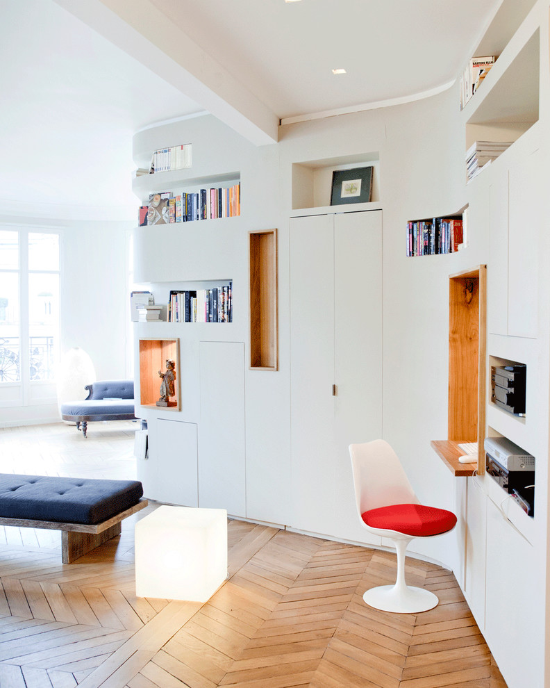 Design ideas for a small contemporary study room in Paris with white walls, light hardwood floors and a built-in desk.