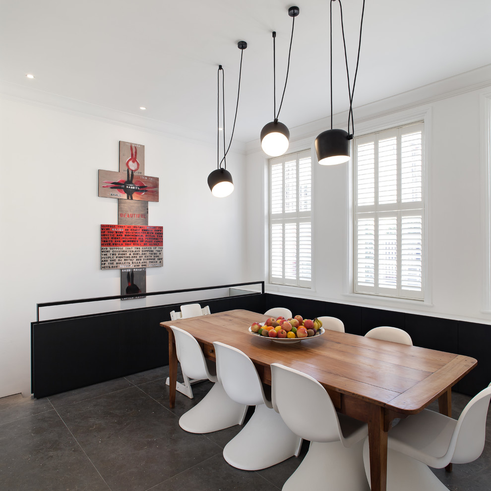 Mid-sized contemporary dining room in London with white walls and grey floor.