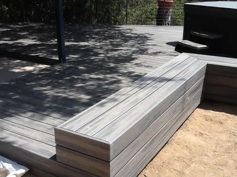 Photo of a large modern backyard deck in Los Angeles with a water feature and a roof extension.