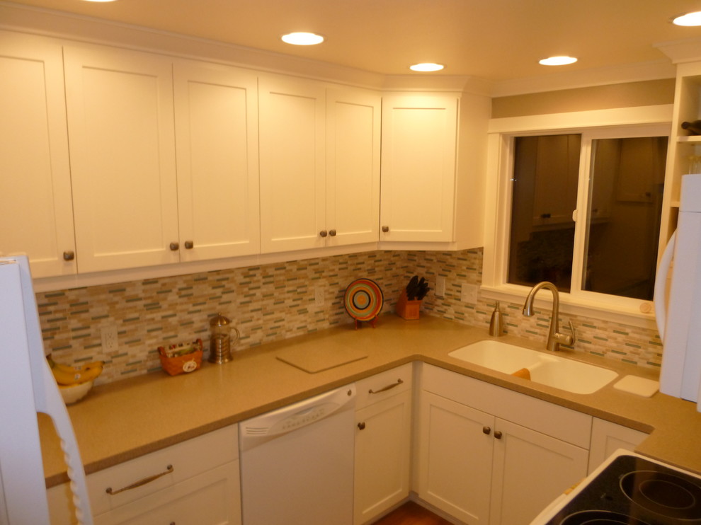This is an example of a small contemporary u-shaped separate kitchen in Other with an undermount sink, shaker cabinets, white cabinets, quartz benchtops, multi-coloured splashback, mosaic tile splashback, white appliances and no island.