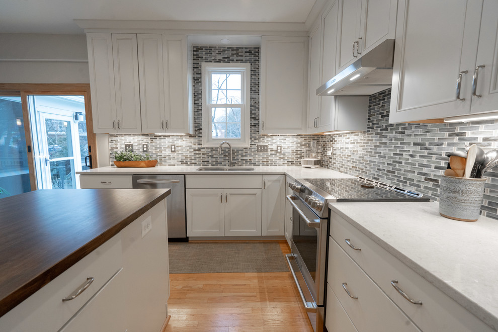 Design ideas for a traditional u-shaped eat-in kitchen in DC Metro with an undermount sink, flat-panel cabinets, white cabinets, quartzite benchtops, multi-coloured splashback, ceramic splashback, stainless steel appliances, light hardwood floors, with island, yellow floor and white benchtop.