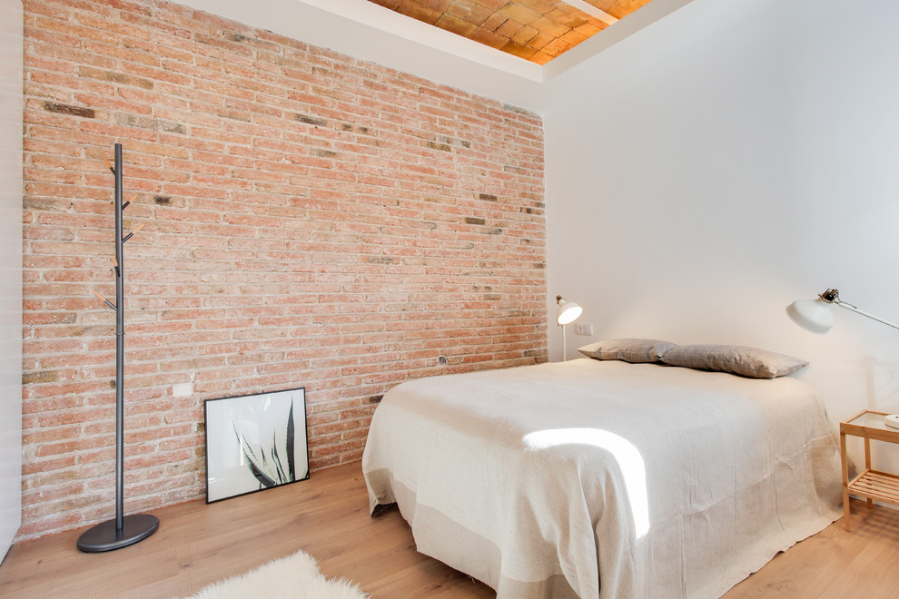 This is an example of a mediterranean bedroom in Barcelona with white walls and light hardwood floors.