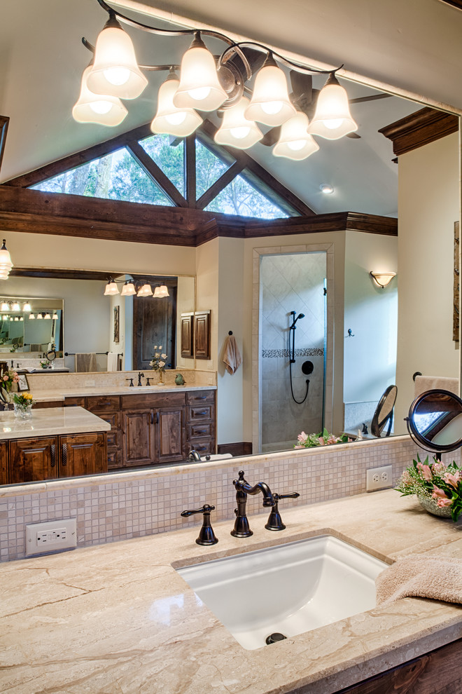 Inspiration for a large traditional master bathroom in Other with raised-panel cabinets, medium wood cabinets, marble benchtops, a drop-in tub, a corner shower, a one-piece toilet, beige tile, stone tile, beige walls, travertine floors, an undermount sink, beige benchtops and a single vanity.
