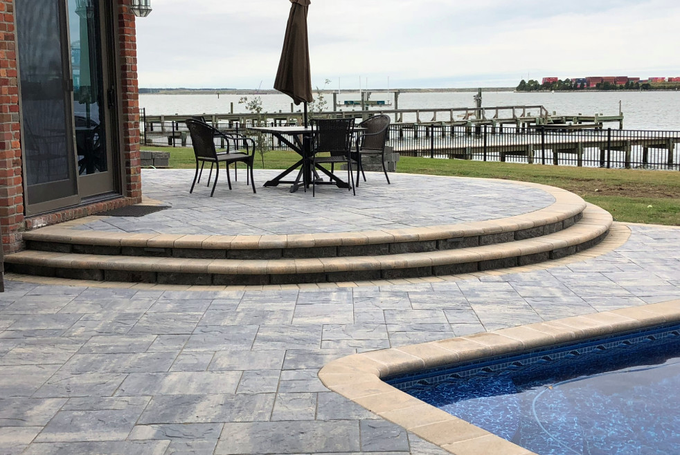 Example of a large transitional backyard stamped concrete patio design with no cover
