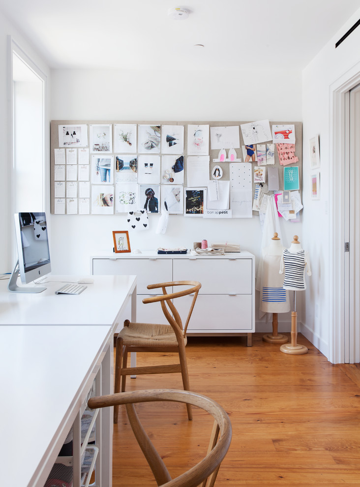 Mid-sized contemporary home studio in New York with white walls, medium hardwood floors, a freestanding desk, no fireplace and brown floor.