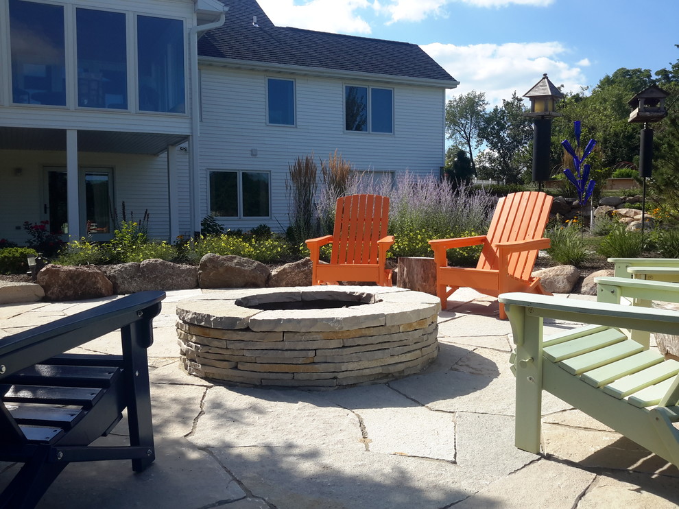 Inspiration for a large traditional backyard patio in Cedar Rapids with a fire feature, natural stone pavers and no cover.