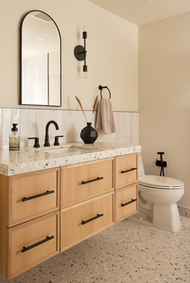 Photo of a mid-sized scandinavian 3/4 bathroom in New York with beaded inset cabinets, light wood cabinets, a one-piece toilet, beige tile, terrazzo floors, an undermount sink, terrazzo benchtops, white floor, multi-coloured benchtops, a single vanity and a floating vanity.