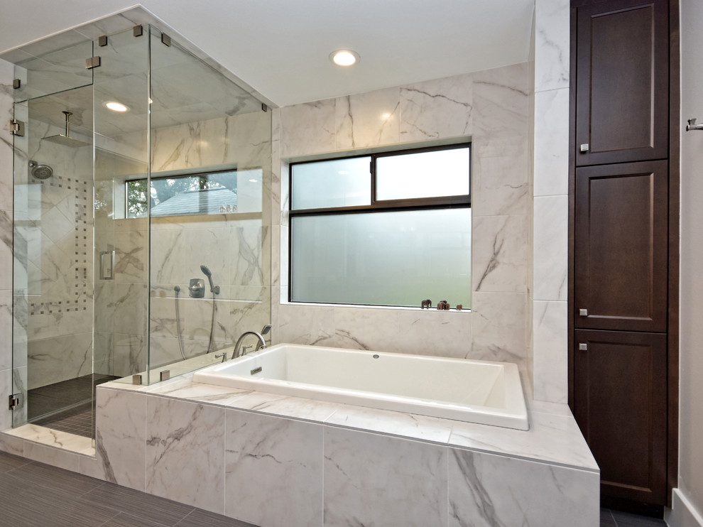 Contemporary bathroom in Austin with shaker cabinets, medium wood cabinets, white tile, marble, an undermount sink, solid surface benchtops, a shower/bathtub combo and a hinged shower door.