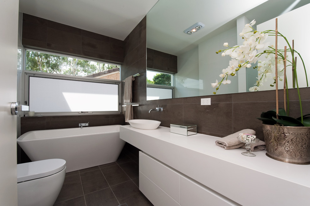 Design ideas for a small contemporary master bathroom in Adelaide with flat-panel cabinets, white cabinets, engineered quartz benchtops, a freestanding tub, an alcove shower, a one-piece toilet, brown tile, porcelain tile, brown walls and porcelain floors.