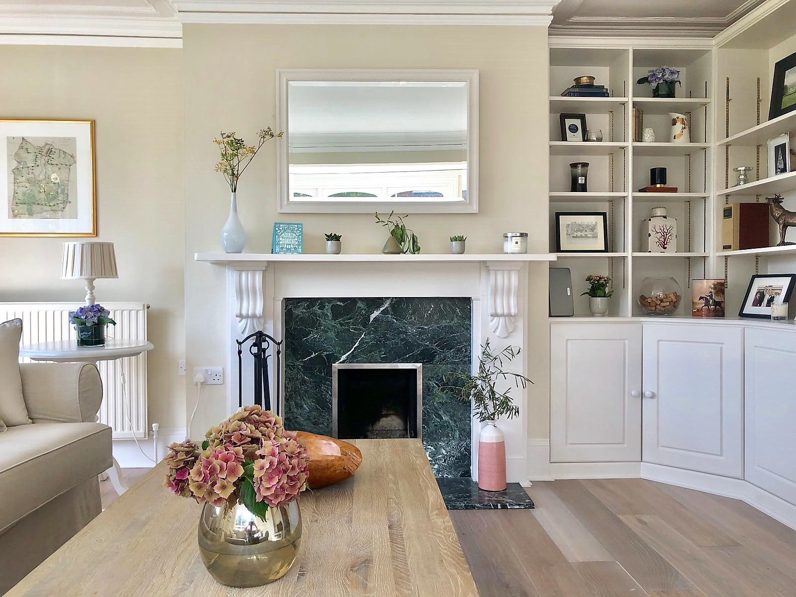 A beautiful traditional living space with high ceilings and edged with decorative coving, decorated with a muted natural palette. Wall to ceiling classic bespoke storage is a featured point of the roo