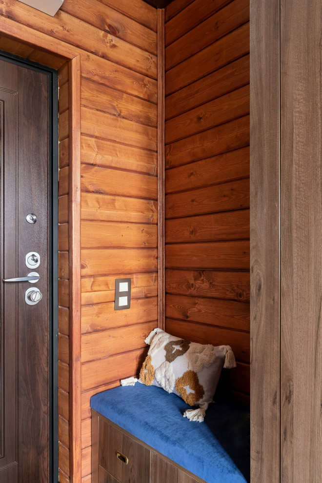 Cette image montre une porte d'entrée marine de taille moyenne avec un mur marron, un sol en carrelage de porcelaine, une porte simple, une porte en bois foncé, un sol beige, un plafond à caissons et du lambris de bois.