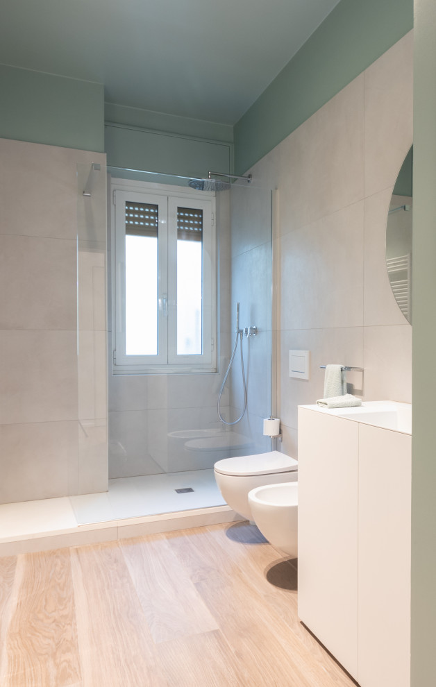 This is an example of a large modern 3/4 bathroom in Milan with flat-panel cabinets, white cabinets, an open shower, a two-piece toilet, white tile, porcelain tile, green walls, an undermount sink, solid surface benchtops, white benchtops, a single vanity, a freestanding vanity and panelled walls.