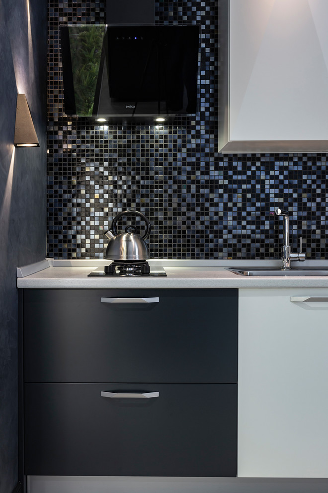 This is an example of a small eclectic single-wall eat-in kitchen in Saint Petersburg with a drop-in sink, flat-panel cabinets, laminate benchtops, black splashback, mosaic tile splashback, black appliances, laminate floors, with island and grey floor.