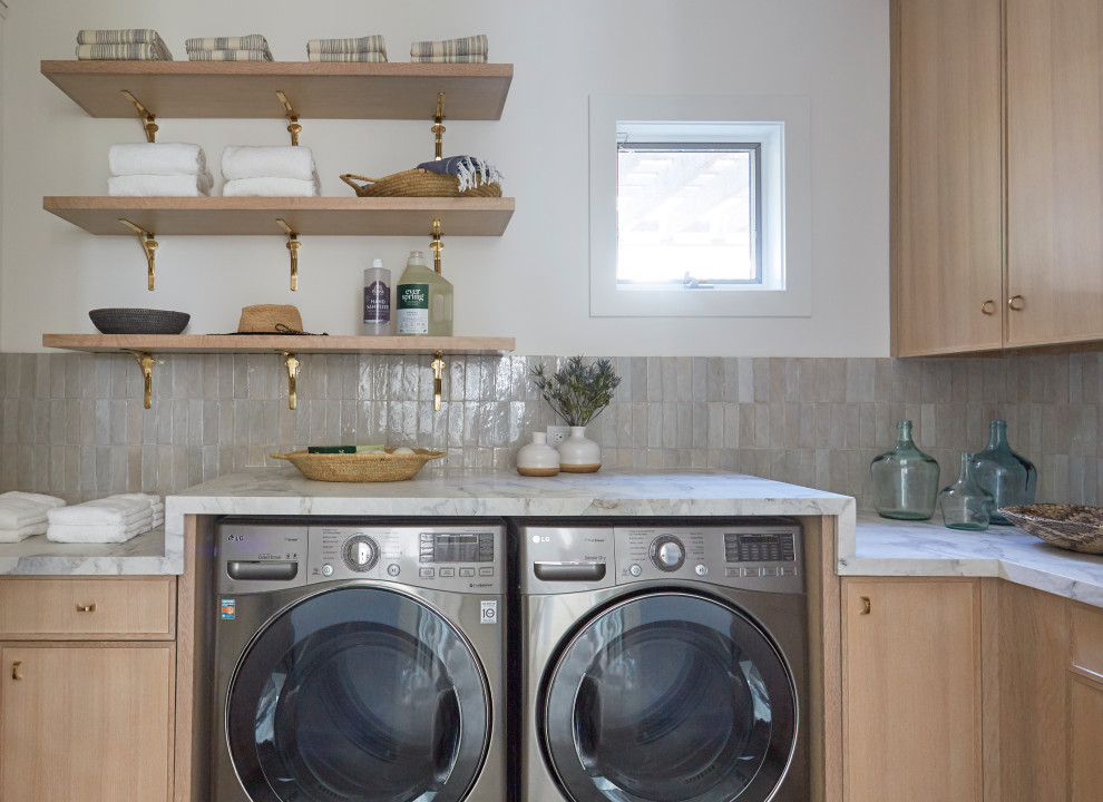 Inspiration for a beach style l-shaped laundry room in Miami with flat-panel cabinets, light wood cabinets, a side-by-side washer and dryer and white benchtop.