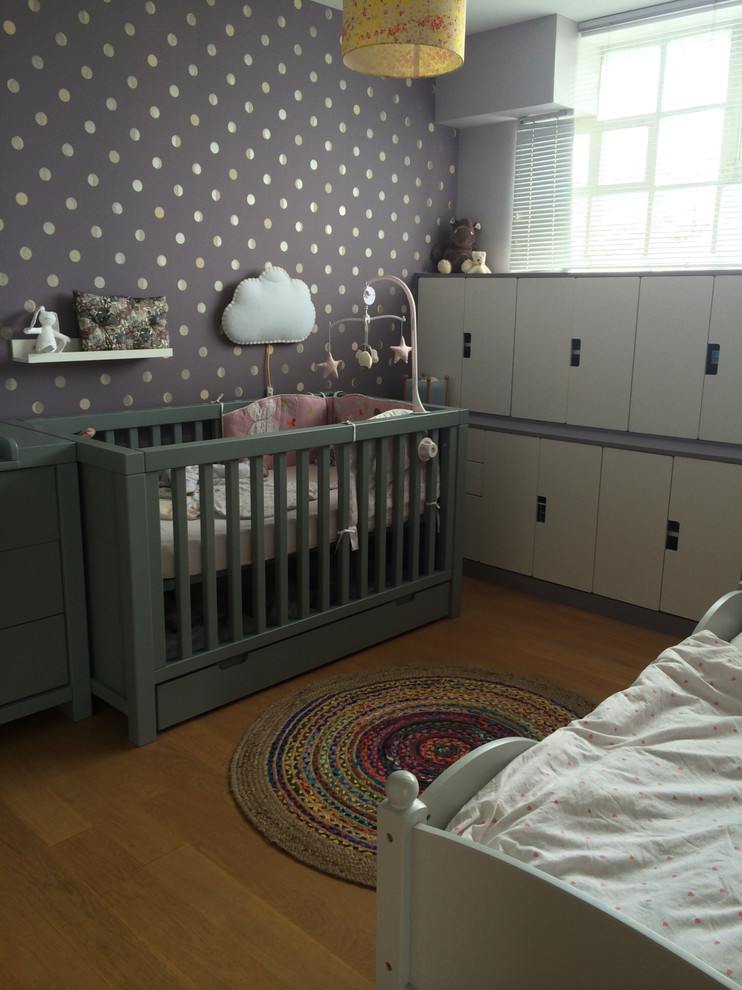 Mid-sized contemporary nursery in Paris with purple walls and light hardwood floors for girls.