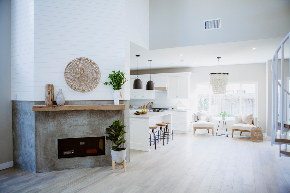 Design ideas for a mid-sized beach style l-shaped open plan kitchen in San Diego with an undermount sink, shaker cabinets, white cabinets, quartz benchtops, white splashback, ceramic splashback, stainless steel appliances, ceramic floors, with island and brown floor.