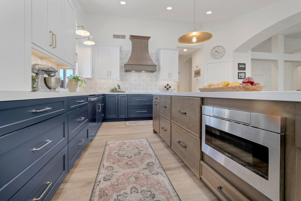 Example of a large transitional l-shaped porcelain tile, brown floor and vaulted ceiling eat-in kitchen design in Phoenix with an undermount sink, shaker cabinets, blue cabinets, quartzite countertops, multicolored backsplash, mosaic tile backsplash, stainless steel appliances, two islands and white countertops