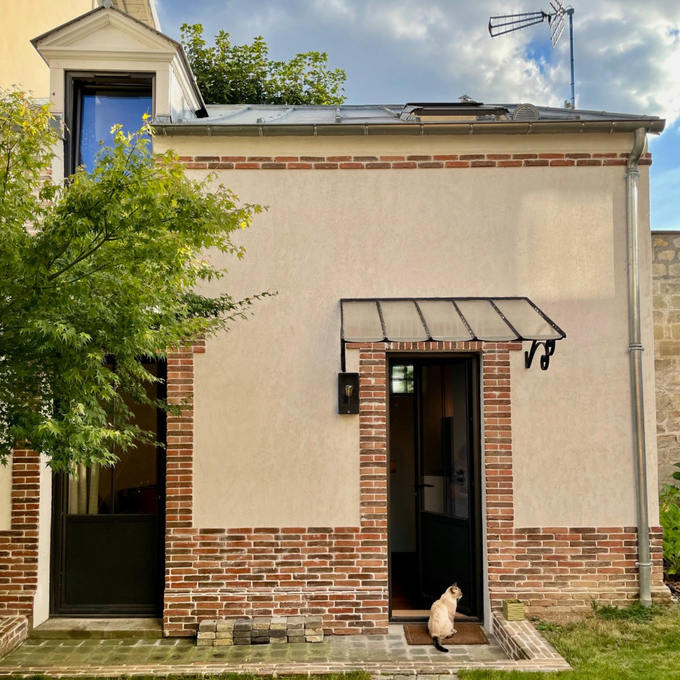 Ejemplo de fachada de casa gris urbana pequeña de dos plantas con revestimiento de ladrillo y tejado de metal