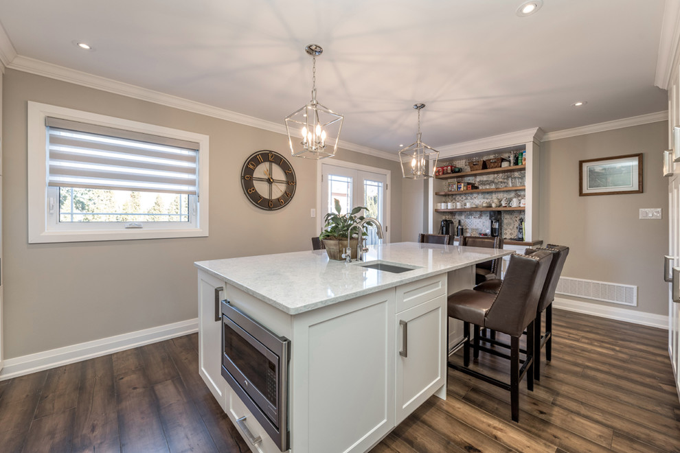 Large transitional galley dark wood floor and brown floor eat-in kitchen photo with an undermount sink, shaker cabinets, white cabinets, quartz countertops, multicolored backsplash, mosaic tile backsplash, stainless steel appliances, an island and multicolored countertops