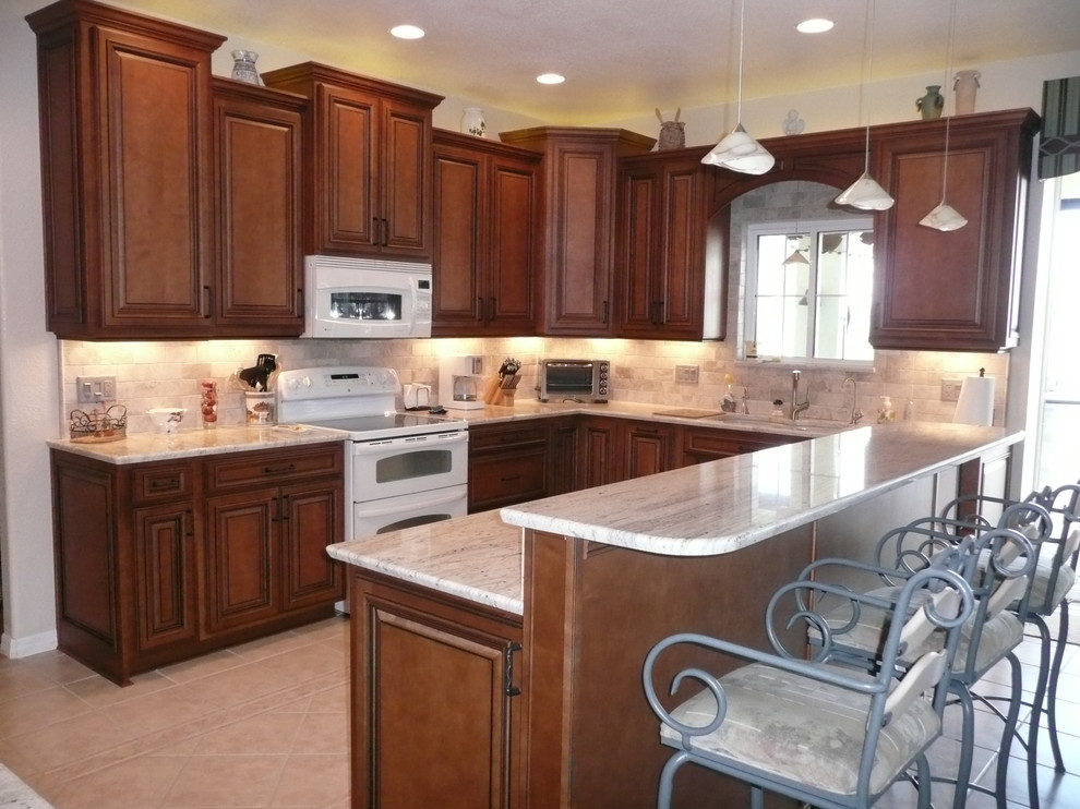 Inspiration for a mid-sized traditional u-shaped eat-in kitchen in Tampa with medium wood cabinets, granite benchtops, white appliances and with island.