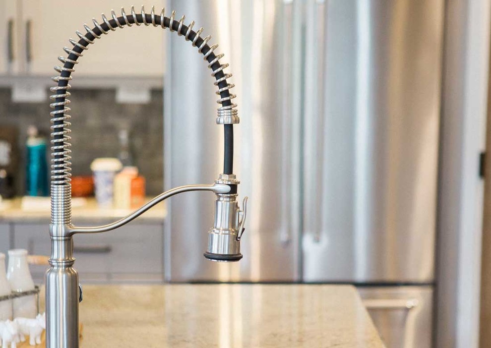 Inspiration for a mid-sized transitional kitchen remodel with a farmhouse sink, granite countertops, gray backsplash, stainless steel appliances and an island