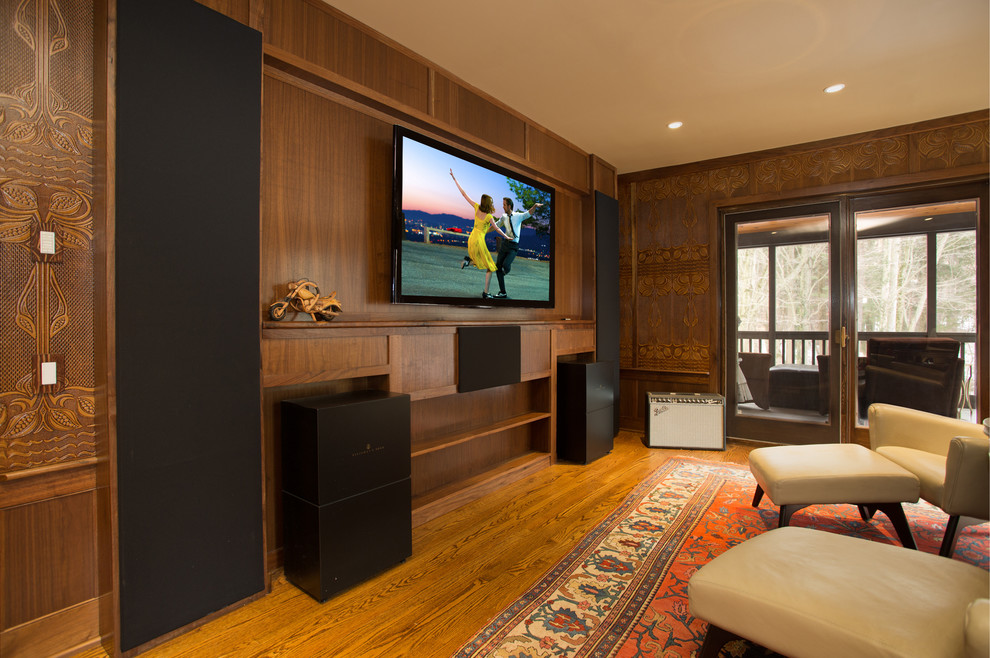 Photo of a mid-sized traditional enclosed home theatre in Other with brown walls, medium hardwood floors, a wall-mounted tv and brown floor.