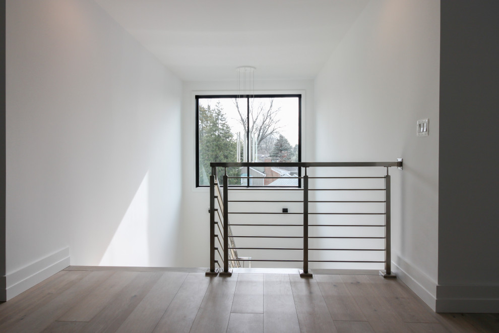 Imagen de escalera suspendida minimalista de tamaño medio con escalones de madera, contrahuellas de madera, barandilla de metal y machihembrado