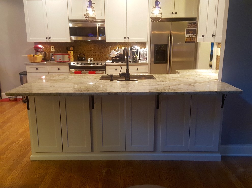 Photo of a mid-sized transitional u-shaped eat-in kitchen in Atlanta with an undermount sink, shaker cabinets, white cabinets, granite benchtops, multi-coloured splashback, glass sheet splashback, stainless steel appliances, light hardwood floors, a peninsula and brown floor.