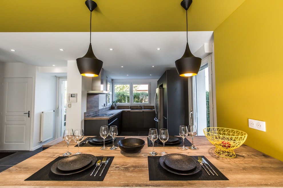 Photo of a mid-sized contemporary u-shaped eat-in kitchen in Lyon with an undermount sink, flat-panel cabinets, black cabinets, laminate benchtops, brown splashback, timber splashback, stainless steel appliances, ceramic floors, with island, grey floor and brown benchtop.