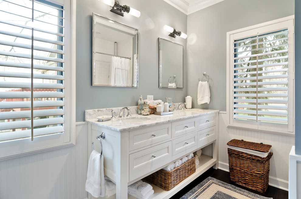 This is an example of a mid-sized transitional bathroom in Chicago with an undermount sink, beaded inset cabinets, white cabinets, marble benchtops, an alcove tub, an alcove shower, a one-piece toilet, white tile, subway tile, blue walls and medium hardwood floors.