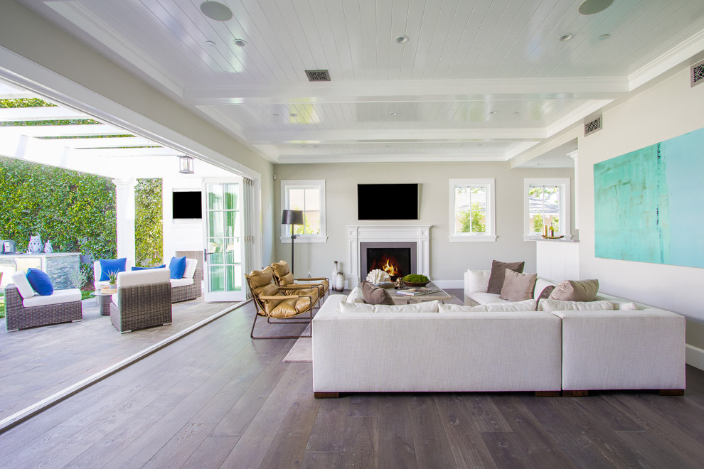 Inspiration for a mid-sized beach style enclosed family room in Los Angeles with grey walls, dark hardwood floors, a standard fireplace, a concrete fireplace surround, no tv and brown floor.