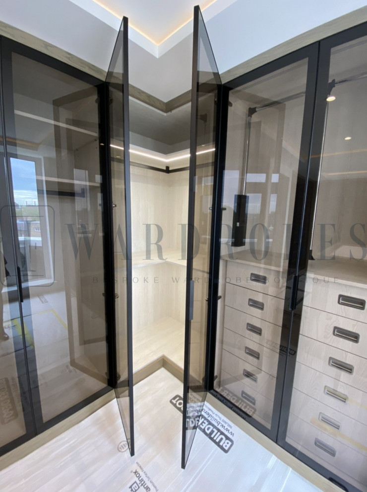 Großes Modernes Ankleidezimmer mit Einbauschrank, Glasfronten und hellen Holzschränken in London