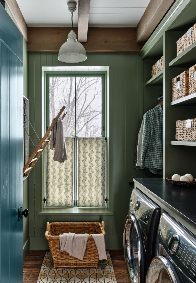 This is an example of a country single-wall dedicated laundry room in Burlington with open cabinets, green cabinets, green walls, dark hardwood floors, a side-by-side washer and dryer, brown floor, black benchtop and planked wall panelling.