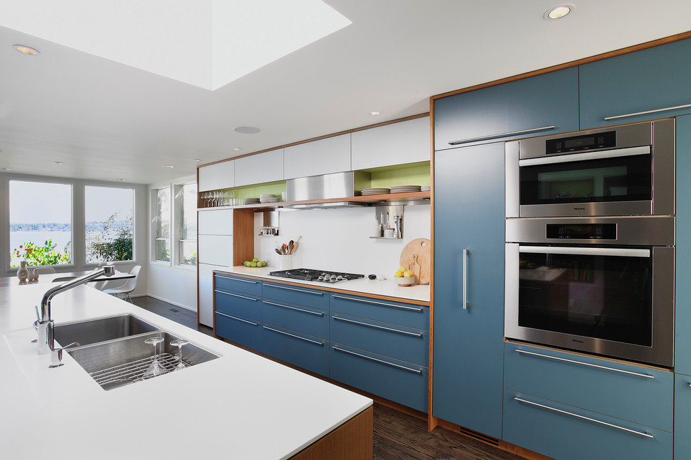 Inspiration for a large contemporary galley eat-in kitchen in Seattle with flat-panel cabinets, stainless steel appliances, a double-bowl sink, blue cabinets, white splashback, dark hardwood floors, with island and brown floor.