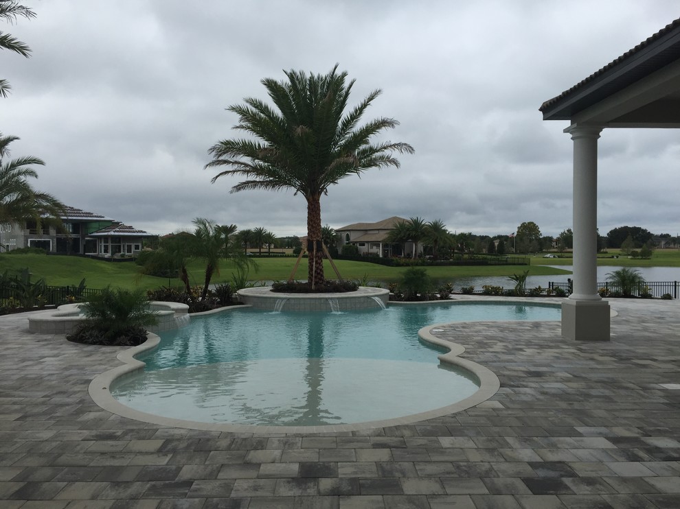 Design ideas for a large transitional backyard custom-shaped pool in Orlando with concrete pavers and a hot tub.