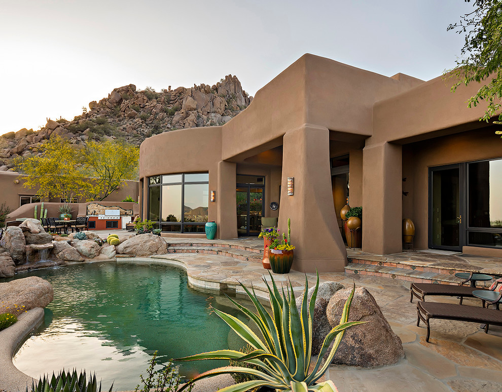 Photo of a backyard custom-shaped natural pool in Phoenix with a water feature.