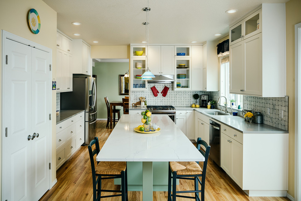 Inspiration for a transitional medium tone wood floor eat-in kitchen remodel with an undermount sink, shaker cabinets, white cabinets, quartzite countertops, gray backsplash, stainless steel appliances, an island and gray countertops