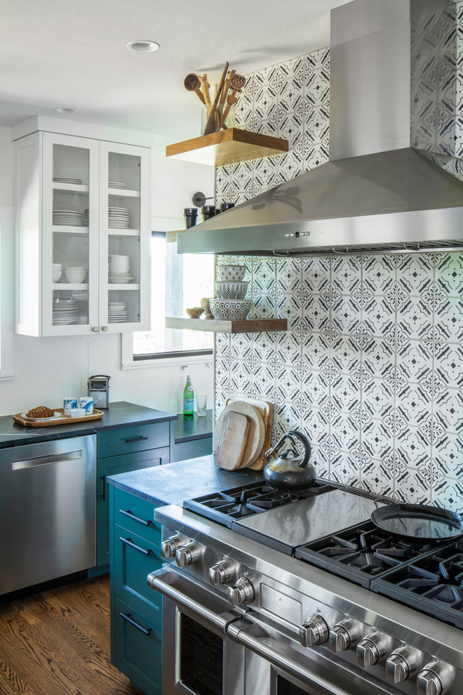 Inspiration for a mid-sized transitional kitchen in Austin with glass-front cabinets, turquoise cabinets, soapstone benchtops, white splashback, ceramic splashback, stainless steel appliances, medium hardwood floors, brown floor and black benchtop.