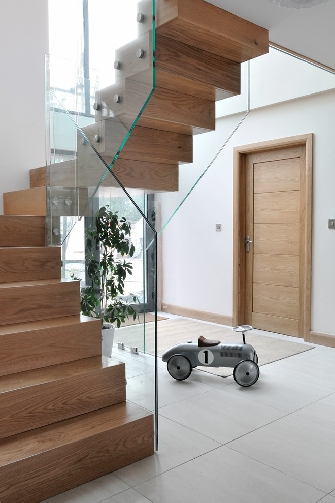 Photo of a large contemporary wood curved staircase in Cardiff with glass railing and wood risers.